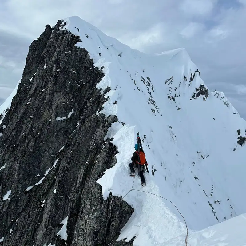Klatrer traverserer luftig alpin vinterrygg