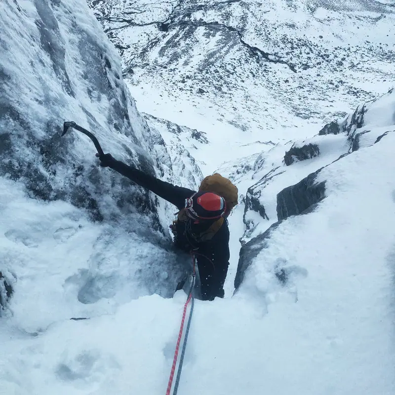 Klatrer med isøks i bratt snørenne, sett ovenfra