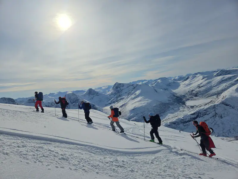 Gruppe på skitur opp mot Romsdalsfjellene i motlys