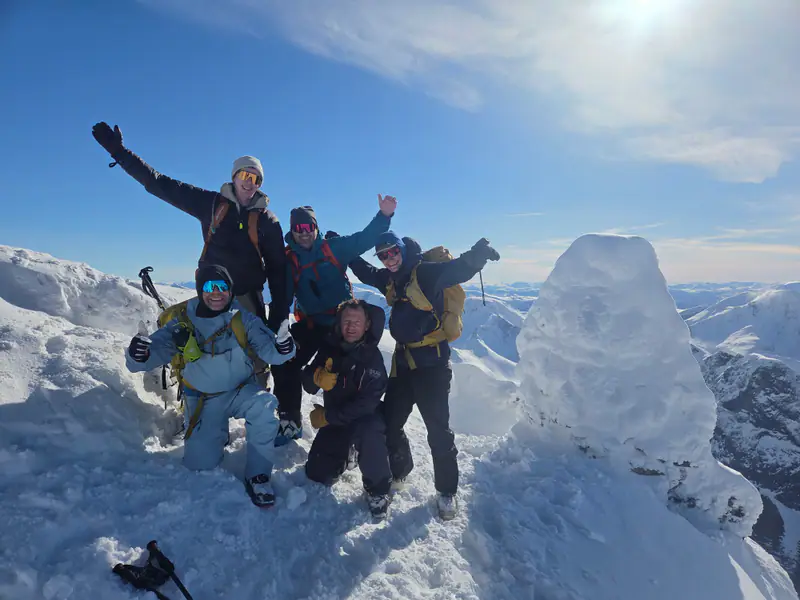 Gruppe jubler på toppen etter topptur i Sunnmørsalpene