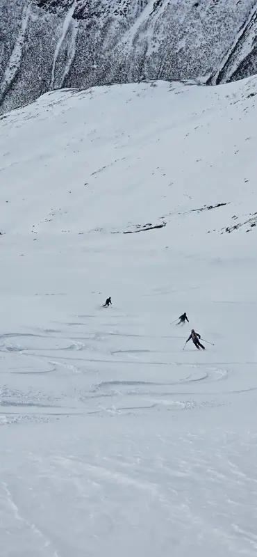 Skiløpere i lang nedkjøring på snøfelt