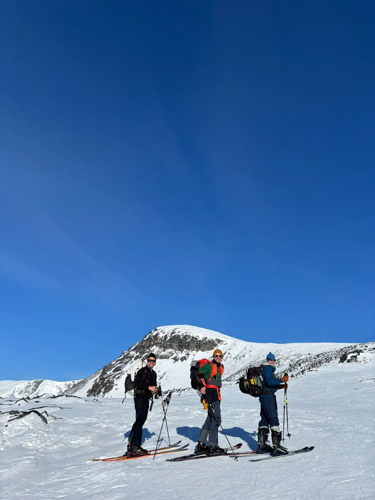 To skiløpere på snøvidde under blå himmel i Jotunheimen